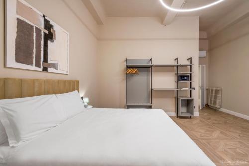 a bedroom with a large white bed and a shelf at Hotel Adamas in Florence