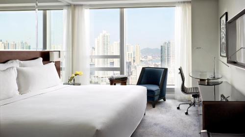 a bedroom with a bed and a desk and a chair at Cordis, Hong Kong in Hong Kong