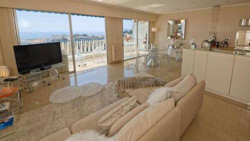 un salon avec un canapé et une télévision à écran plat dans l'établissement CANNES Vue Mer, à Cannes