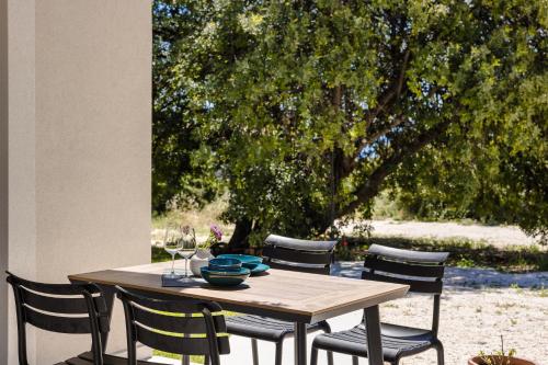 a wooden table with four chairs around it with a tree at Rodi Studios in Karavadhos