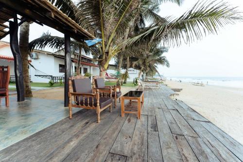 a wooden deck with chairs and a table on the beach at Saman Beach Guest House in Galle