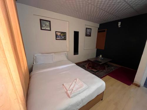 a bedroom with a white bed with a pink pillow on it at Saanvi Hotel & Restaurant in Kathmandu