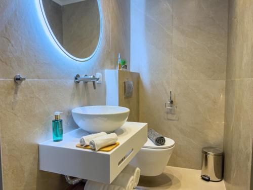 a bathroom with a sink and a toilet and a mirror at Luxury Rooms Naoum - Adults only in Limenaria