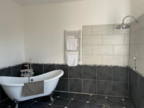 a bathroom with a white tub and black tiles at Cantaranne in Privezac