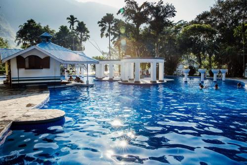 奇旺Riverside Springs Resort的蓝色海水游泳池和凉亭