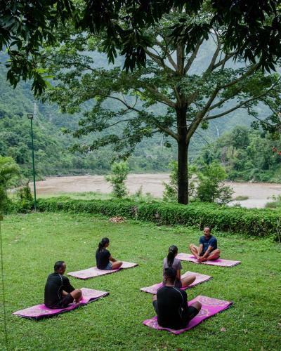 a group of people sitting on mats in the grass at Riverside Springs Resort in Chitwan