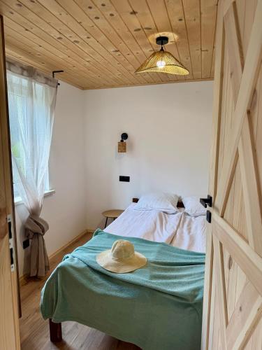 a bedroom with a bed with a hat on it at Domki przy lesie 300m od jeziora 509-619-803 in Zawóz
