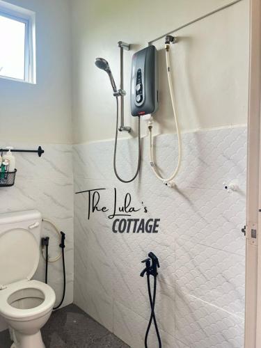 a bathroom with a toilet and a phone on the wall at The LuLas Cottage in Malacca