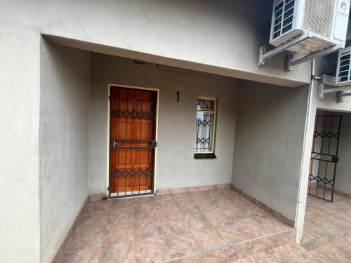 an empty room with a door and two windows at Guest Apartments in Ezulwini