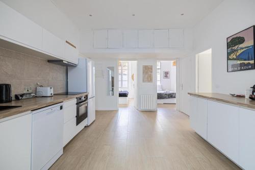 une cuisine avec des armoires blanches et un plancher en bois dans l'établissement LE WINDSOR avec extérieur, spacieux et chaleureux pour un plaisir partagé, à Cannes