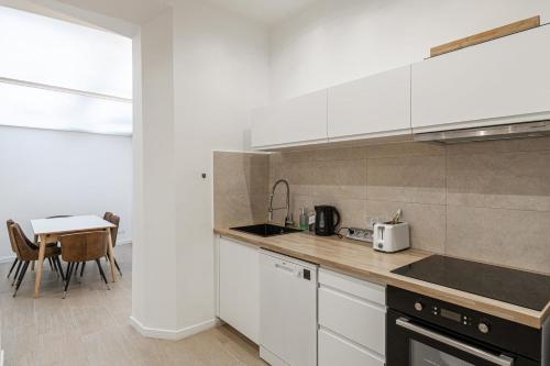 une cuisine avec des armoires blanches et une table dans l'établissement LE WINDSOR avec extérieur, spacieux et chaleureux pour un plaisir partagé, à Cannes