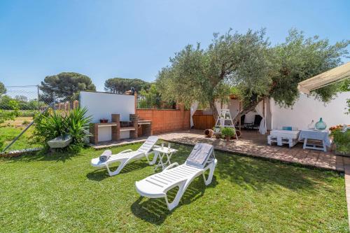 a backyard with lawn chairs and a table and a tree at Casa Rural Pozo Viejo in Marchena