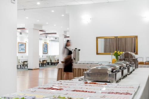 a woman walking through a cafeteria with a buffet of food at Hotel Artur in Kraków