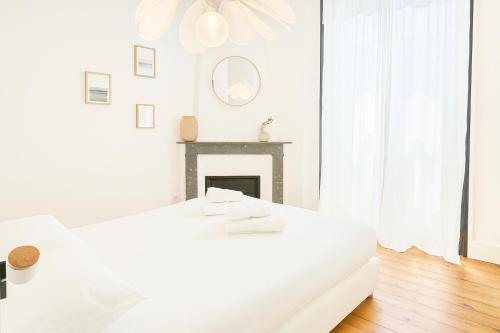 - une chambre blanche avec un lit blanc et une cheminée dans l'établissement Élégant cocon avec balcon à deux pas des vagues, à Biarritz
