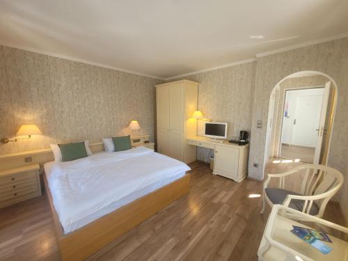 a bedroom with a bed and a desk and a television at SEE-Hotel Seeschau - direkt am Bodenseeufer in Reichenau