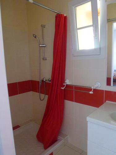 La salle de bains est pourvue d'une douche avec rideau de douche rouge. dans l'établissement Maison au calme, à Rochefort
