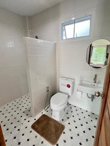 a white bathroom with a toilet and a sink at บุณยาเพลส เด่นชัย แพร่ in Den Chai