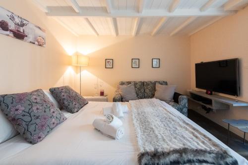 une chambre avec un lit blanc et une télévision à écran plat dans l'établissement LE RIMBAUD splendide duplex dans le Suquet, près des plages et du Palais des Festivals, à Cannes