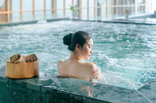 a woman in a swimming pool with a box of shoes at Flamingo Hải Tiến Tầng 15 View Hướng Biển, Cực Chill in Thanh Hóa