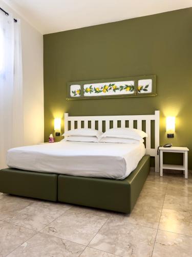 a bedroom with a large bed with green walls at San Domenico Residence by BADIA NUOVA in Trapani