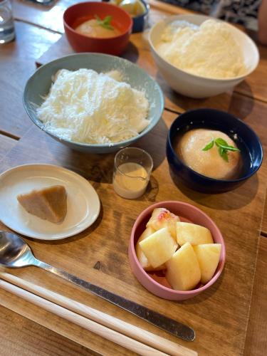 a wooden table topped with bowls of food and chopsticks at Kamakura Jomyoji Terrace-鎌倉浄明寺テラス- in Kamakura