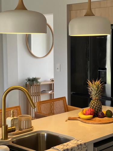 a kitchen with a sink and a pineapple on a cutting board at Wait and Sea Bargara in Bargara