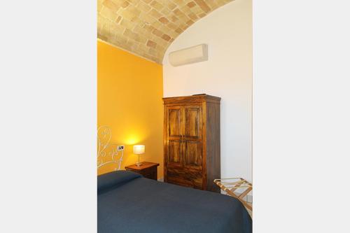 a bedroom with a bed and a wooden cabinet at La Casa Del Palombaro in Ortona