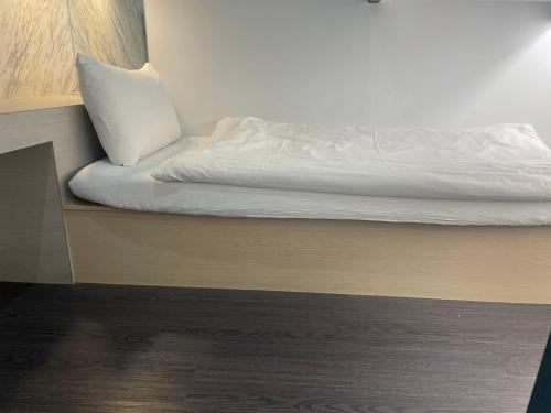 a bed with white sheets and a pillow on it at 苓旅松山館 Lininn Tapei Arena in Taipei