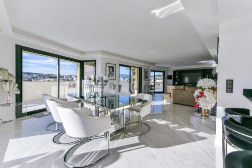 une salle à manger avec une table en verre et des chaises blanches dans l'établissement L'HORIZON avec somptueuse terrasse vue mer, à Cannes