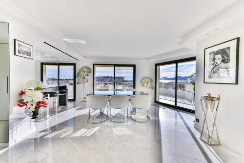 un salon blanc avec une table et des chaises dans l'établissement L'HORIZON avec somptueuse terrasse vue mer, à Cannes
