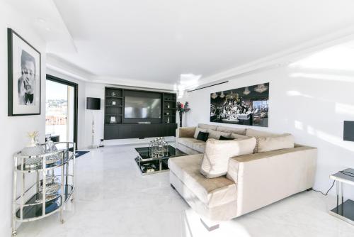 un salon blanc avec un canapé et une télévision dans l'établissement L'HORIZON avec somptueuse terrasse vue mer, à Cannes