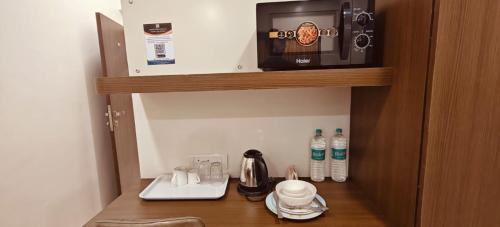 ムンバイにあるTIM Santacruz Mumbai Airportの棚にコーヒーメーカーと電子レンジが置かれた部屋