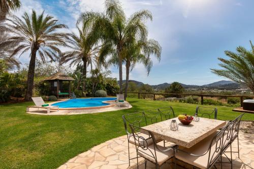 a patio with a table and chairs and a pool at Villa Beni - Santa Eulalia in Santa Eularia des Riu
