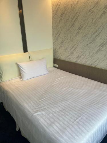 a bed with a white pillow on top of it at 苓旅松山館 Lininn Tapei Arena in Taipei