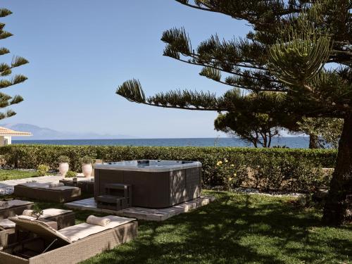 a backyard with a hot tub and a tree at Sea Elegance Villa - On the Beach, by ZanteWize in Zakynthos Town