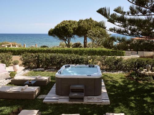 a hot tub sitting in the grass near the ocean at Sea Elegance Villa - On the Beach, by ZanteWize in Zakynthos Town