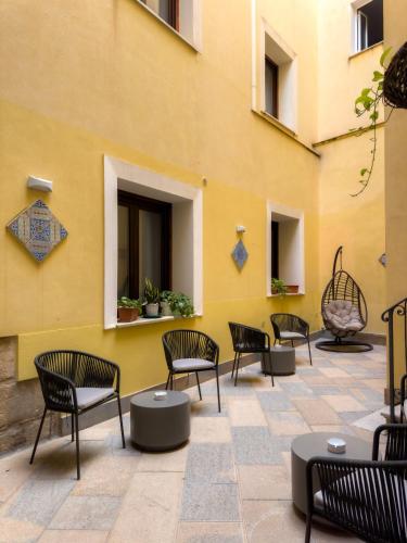 a group of chairs sitting next to a yellow building at San Domenico Residence by BADIA NUOVA in Trapani
