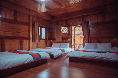 three beds in a room with wooden walls at Bắc Hà Green Homestay & Coffe in Kon Rung (1)
