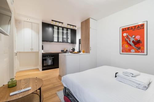 Cet appartement comprend une chambre avec un lit blanc et une cuisine. dans l'établissement Studio parisien coeur montmartre - Paris 18 - 2p, à Paris