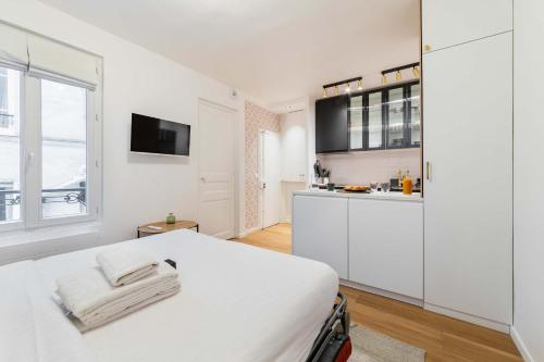 une chambre blanche avec un lit et une cuisine dans l'établissement Studio parisien coeur montmartre - Paris 18 - 2p, à Paris