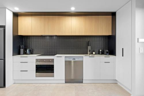 a kitchen with white cabinets and stainless steel appliances at Stylish Stay Heart of the CBD in Christchurch