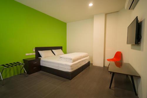 a green bedroom with a bed and a red chair at 客旅家青年旅館 Travelers Plus in Chiayi City