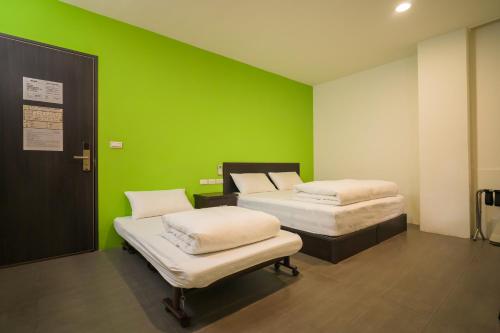 two beds in a room with a green wall at 客旅家青年旅館 Travelers Plus in Chiayi City