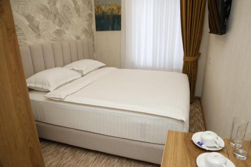a bedroom with a white bed and a table at Clouds Hotel in Tashkent