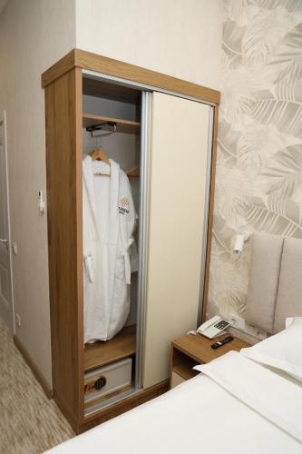 a wardrobe with a mirror and a white shirt in it at Clouds Hotel in Tashkent