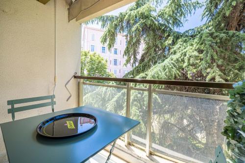 une table bleue sur un balcon avec vue sur un arbre dans l'établissement LE CENTER avec joli balcon et parking pour un plaisant séjour, à Cannes