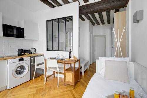 Il comprend une cuisine et un salon avec une table et un lave-linge. dans l'établissement suite Joyful Ivy - Cozy apartment in Paris, à Paris