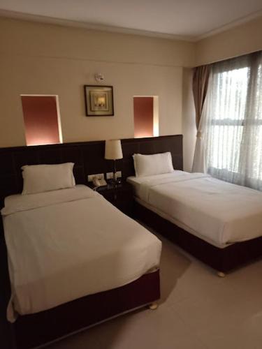 a hotel room with two beds and a window at The Citiotel, Shivaji Nagar in Pune
