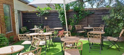 a patio with tables and chairs and an umbrella at Hotel des Iris in Auvers-sur-Oise