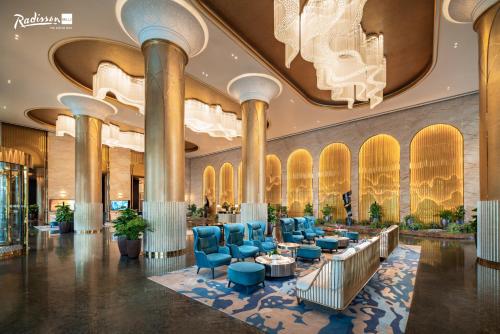 a lobby of a hotel with blue chairs and tables at Radisson Blu Ha Long Bay in Ha Long